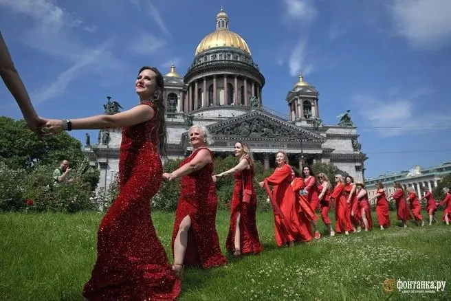 Женщины в красных платьях выстроились в форме сердца в Санкт-Петербурге в рамках акции, зародившейся в Красноярске. Организаторы обещали завтраки, танцы и фотосессии; участие платное.