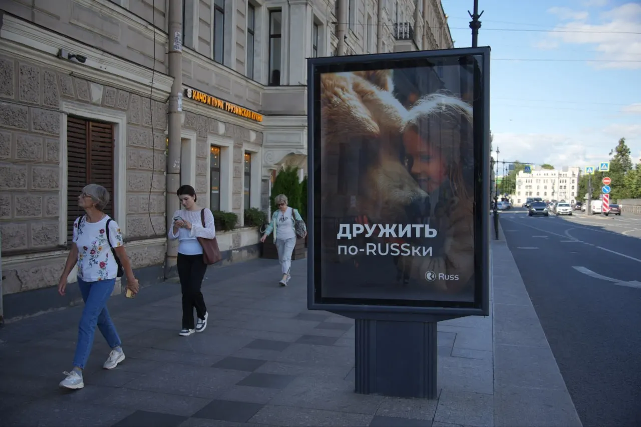 Баннер с цитатой из рэп‑трека убрали — вместо него появился рекламный плакат с надписью «Дружить по‑RUSSки» и изображением ребёнка с медведем.